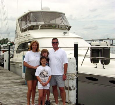 A family posing for the camera in front of a boat.